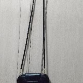 黒トップスとポシェットの画像