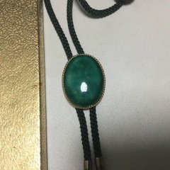 緑色の飾りのついた紐ネクタイの画像