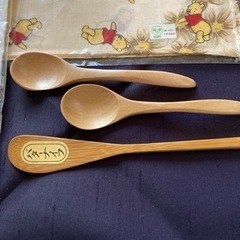 木製スプーン、バターナイフとクマのプーさんのハンカチとフルーツ柄のナフキンの画像