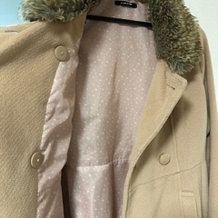 ダブルボタンのファー付きベージュのコートの画像