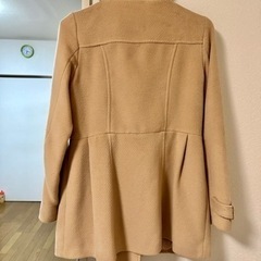 ダブルボタンのファー付きベージュのコートの画像