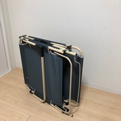 折りたたみベッド、折りたたみの椅子、ガラステーブル、壁掛けのアートの画像