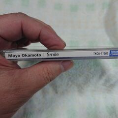 ♣　Smile 岡本真夜 　かすかな哀しさを内包したヴォーカルによる明るく元気なポップンロールこそ、ガールポップの典型だったと思い出させる岡本真夜です。夢を見るお年頃の女のコのラヴ・ソングが、けなげに男のコを励ます時代なのですね。岡本真夜が写した写真集付き。の画像