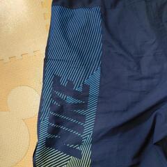 ナイキ　DRI-FIT素材のネイビーボトムス、サイドにロゴとストライプデザイン。の画像