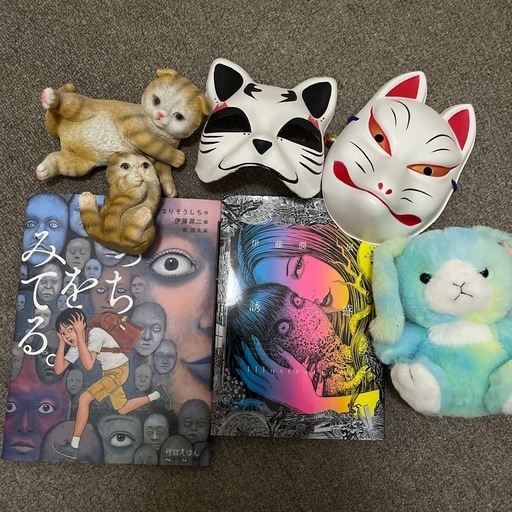 漫画、猫の像、キツネのマスク、ウサギのぬいぐるみ