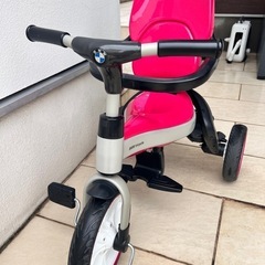 BMW製のピンクの三輪車、調整可能なハンドル付き。の画像