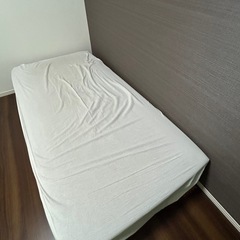 ニトリのマットレス付きシングルベッドとシーツの画像