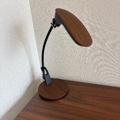 オフィスチェア 黒、木目調デスク、電気スタンドの画像