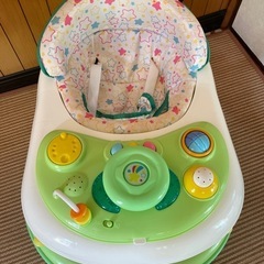 ドット柄のクッションとおもちゃ付きの緑の歩行器。の画像