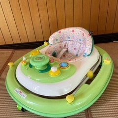 ドット柄のクッションとおもちゃ付きの緑の歩行器。の画像