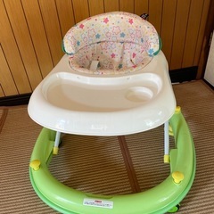 ドット柄のクッションとおもちゃ付きの緑の歩行器。の画像