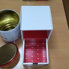 スヌーピーの缶２つと段ボールの引き出しの画像