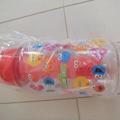 新品箱入り保冷機能付きSESAME STREET × YAMADA タンブラーです。 エルモなどのキャラクターがデザインされた透明なプラスチック製のタンブラーで真ん中の赤い部分を凍らせて保冷することが出来ます。の画像