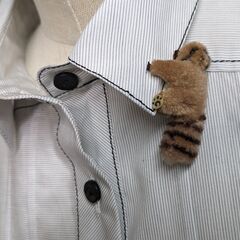両手で挟んで止める小さなぬいぐるみのブローチの画像