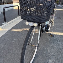 Panasonic製のシルバー電動アシスト自転車、バスケットと前照灯付き。の画像