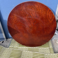 円形の木製座卓、折りたたみ可能でダークブラウンの仕上げ。の画像