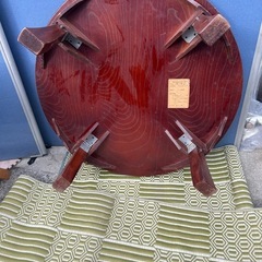 円形の木製座卓、折りたたみ可能でダークブラウンの仕上げ。の画像