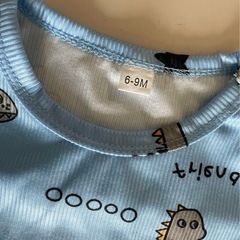 恐竜プリントの青いTシャツとショートパンツのセット。の画像