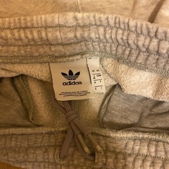 グレーのadidasジョガーパンツ、サイドジッパーポケットの画像