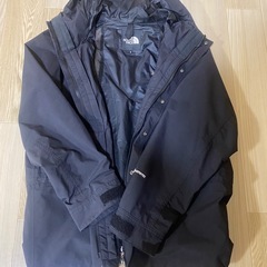 フード付きのネイビーのジャケット、THE NORTH FACEのロゴ入りの画像