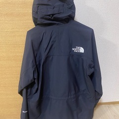 フード付きのネイビーのジャケット、THE NORTH FACEのロゴ入りの画像
