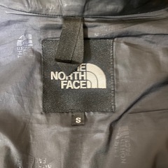 フード付きのネイビーのジャケット、THE NORTH FACEのロゴ入りの画像