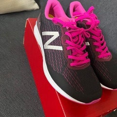 ニュー
バランスの黒とピンクのランニングシューズ。の画像