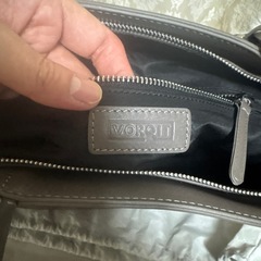 グレーのVORQITトートバッグ、内側にポケットとファスナー付き。の画像