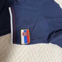 大阪・関西万博セルビア館のセルビア人スタッフ用ポロシャツ。ベオグラード万博2027ピンバッジ付きの画像