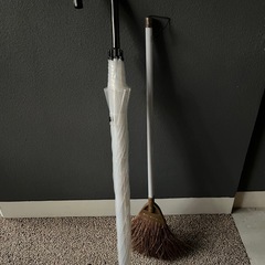 大きめのビニール傘とホウキの画像