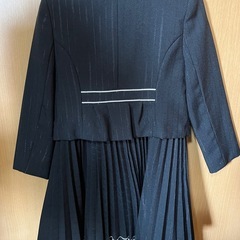 120cmストライプ柄の黒いジャケットとプリーツスカートのセット。の画像