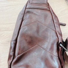 ブラウンレザー製のボディバッグ、ジッパーポケット付き。の画像