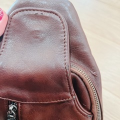 ブラウンレザー製のボディバッグ、ジッパーポケット付き。の画像