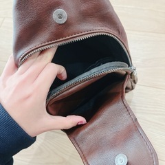 ブラウンレザー製のボディバッグ、ジッパーポケット付き。の画像