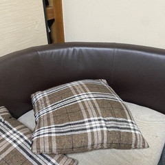 グレーのソファで、背もたれはレザー素材です。の画像