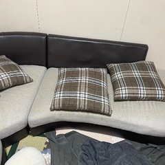 グレーのソファで、背もたれはレザー素材です。の画像