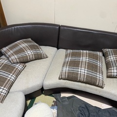 グレーのソファで、背もたれはレザー素材です。の画像