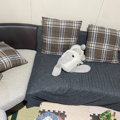 グレーのソファで、背もたれはレザー素材です。の画像