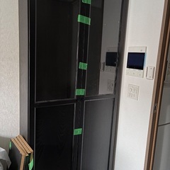 作業デスクとIKEAのガラス扉付き本棚の画像