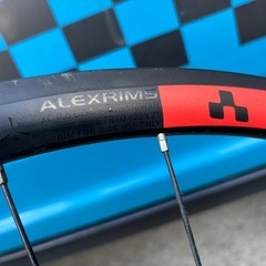 ALEXRIMS XC 30の黒いリアホイール、ディスクブレーキ対応、赤いロゴが特徴。の画像