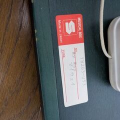 壁掛けタイプのオルゴールと木製の椅子（飾り）の画像