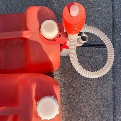 灯油缶二つと給油ホースの画像