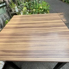 木目調の合成樹脂製ダイニングテーブル、金属脚付きで耐久性あり。  の画像