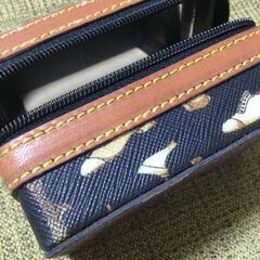 黒地に金色の靴の柄が特徴的な小物入れ。の画像