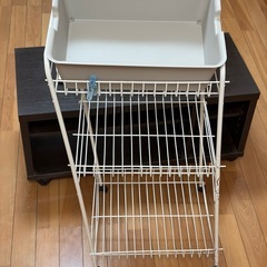 テレビ台とIKEAの時計と壊れたランドリーラックと蓋付きのカゴの画像