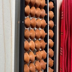 木製そろばんと赤いチェック柄ケースの画像